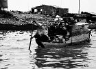 River Shop  A Cambodian woman polls her boat down the Mekong River in Cambodia.  This is just one of the many boats running up and down the river acting as shops selling to the people who live along the river. : Cambodia